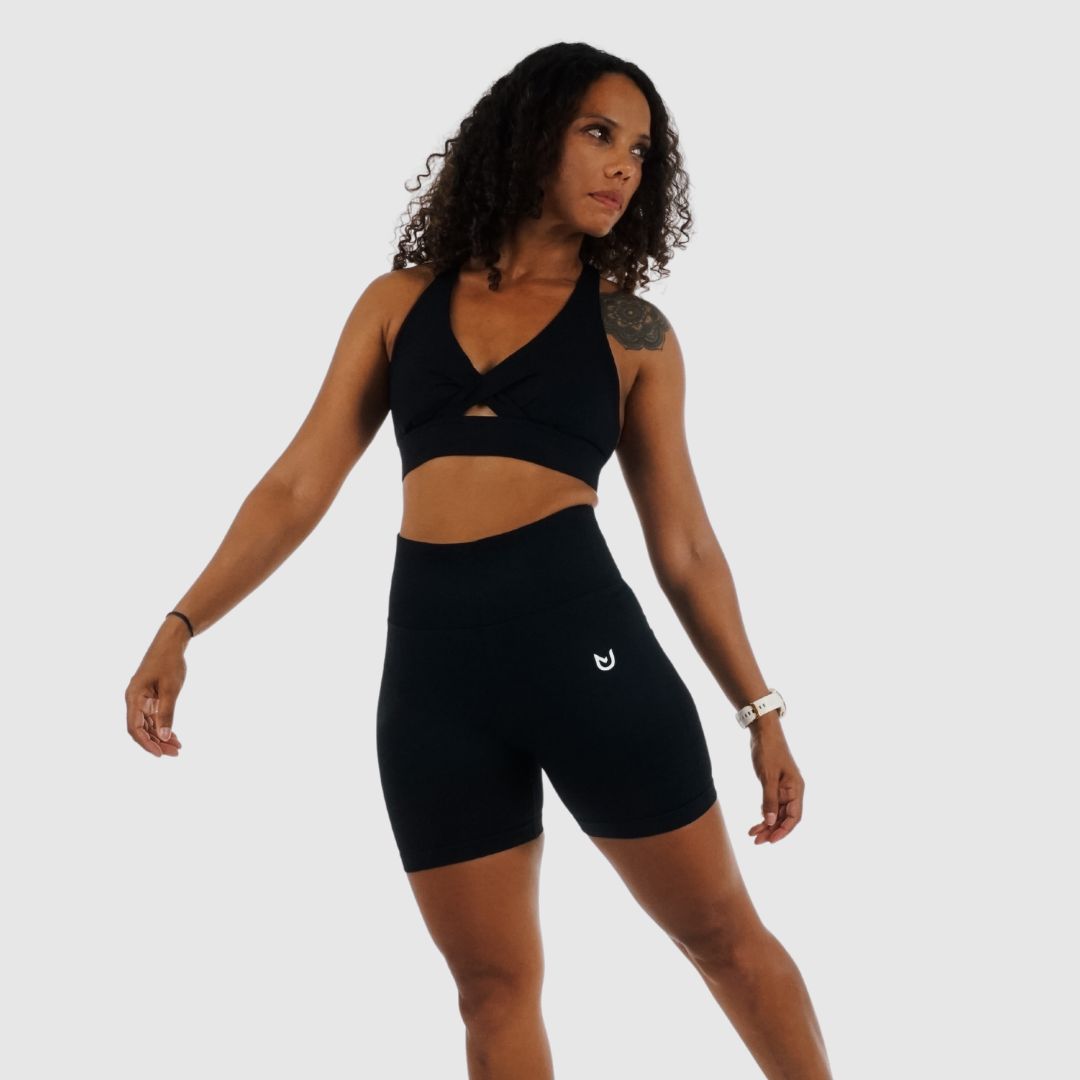 Rückansicht schwarzer High-Waist-Shorts mit scrunch-Naht – sportliche Figur, weiße Sneaker.