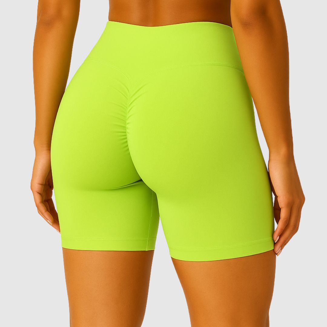 Frau trägt limegrüne Scrunch Shorts mit hohem Bund und passendem Sport-Bra auf weißem Hintergrund